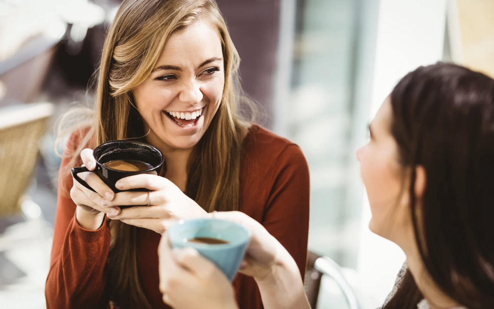 A female professional sitting on the stairs of her caravan, with a laptop on her lap, facing outside towards the mountains during sunset.